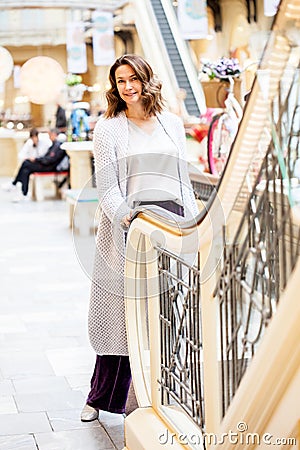woman in a blue knitted coat near an escalator in a shopping center Stock Photo