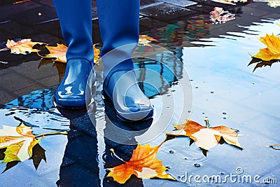 Woman in blue rain boots standing in puddle Stock Photo