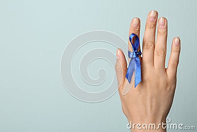 Woman with blue ribbon on against light background, closeup. Symbol of social and medical issues Stock Photo
