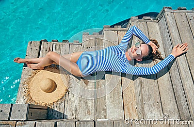 Woman in rash guard on wooden jetty Stock Photo