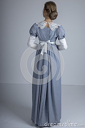 Regency woman in blue striped dress on plain background Stock Photo