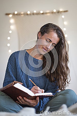 Woman in blue sweater making notes in her journal Stock Photo