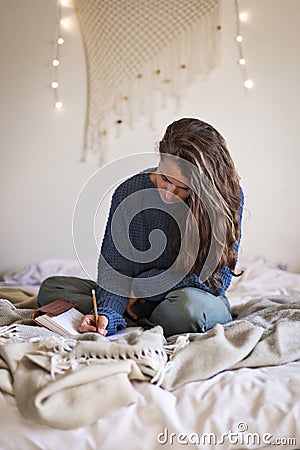 Woman on bed writing in her journal Stock Photo