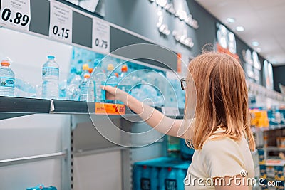 Young blonde cheerful woman picks out a bottle of drinking water at the supermarket Stock Photo