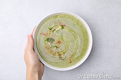Woman with bowl of delicious broccoli cream soup at table, top view Stock Photo