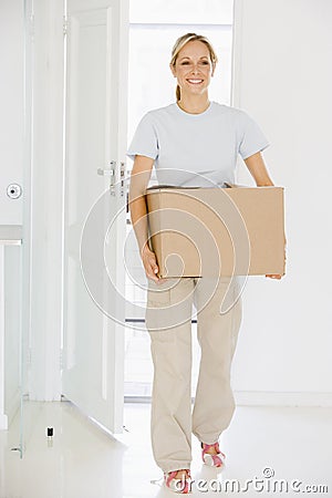 Woman with box moving into new home smiling Stock Photo