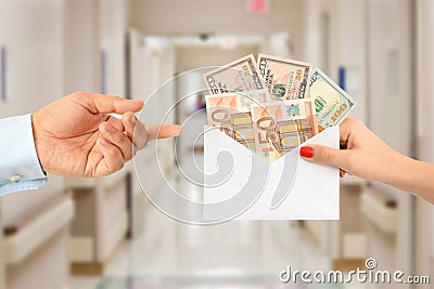 Woman bribing a man with an envelope full of money suggesting a corrupt healthcare system Stock Photo