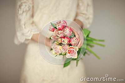 Woman bride hands holding spring flowers tulips and roses, boho wedding dress Stock Photo