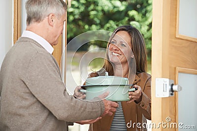 Woman Bringing Meal For Elderly Neighbour Stock Photo