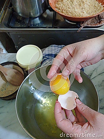 Woman broking egg to prepare cake Stock Photo