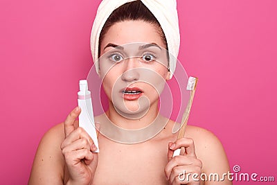 Woman brushing her teeth with shocked facial expression, girl with toothbrush on pink studio background, lady with white Stock Photo