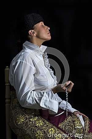 Woman Bullfighter in Chapel praying with Rosary Stock Photo