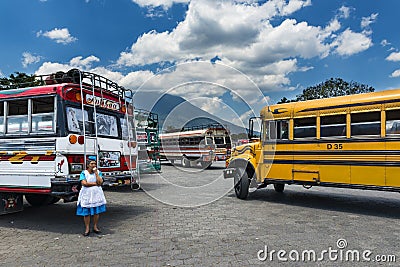 Woman in a bus terminal with colorful buses in Antigua, Guatemala Editorial Stock Photo
