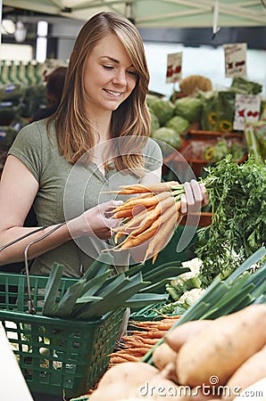 Woman Buying Carrots At Market Vegetable Stall Stock Photo
