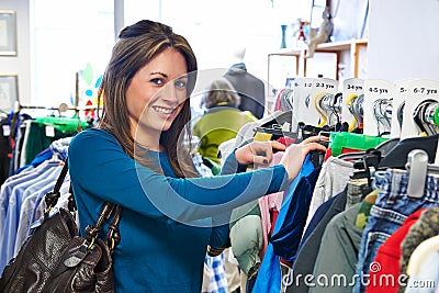 Woman Buying Children's Clothes In Charity Shop Stock Photo