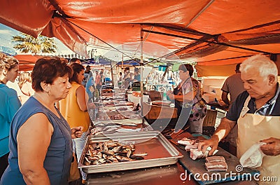 Woman buying fresh fish on street market of the popular fishing town Editorial Stock Photo
