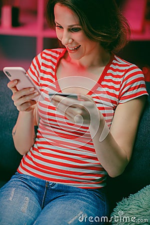 Woman are buying online with a credit card and smile while sitting on the sofa at home. Woman are using smart phone and Stock Photo
