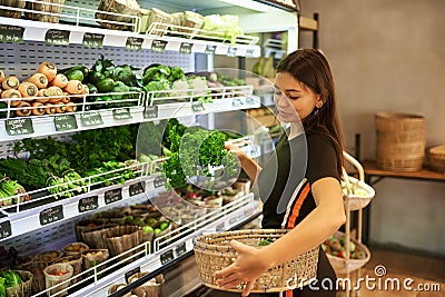 Woman Buying Fresh Fruit And Vegetables In Sustainable Plastic Free Grocery Store Stock Photo
