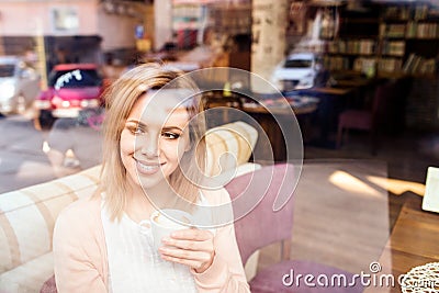 Woman in cafe drinking coffee, street reflection in window Stock Photo