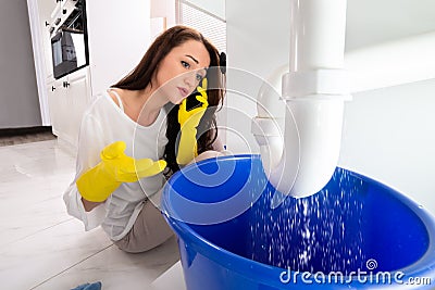 Woman Calling Plumber To Fix Sink Pipe Leakage Stock Photo