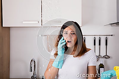 Woman Calling To Plumber For Water Leakage Problem Stock Photo