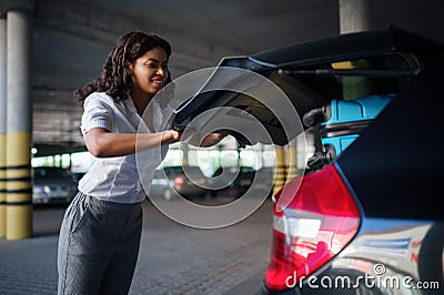 Woman can`t close trunk with suitcases, parking Stock Photo