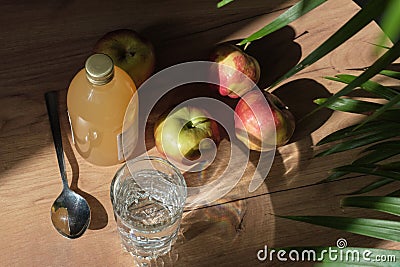 woman carefully pours apple cider vinegar into a spoon, adding it to a glass of water to create a healthy, invigorating Stock Photo