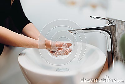 Woman carefully washing hands with soap and sanitiser in home bathroom Stock Photo