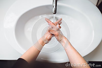 woman carefully washing hands with soap and sanitiser in home bathroom. top view, details of hygiene Stock Photo