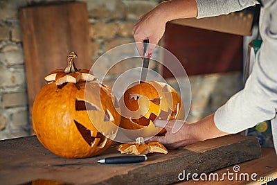 Woman carving Halloween pumpikn; Halloween pumpkin with a carved face Stock Photo