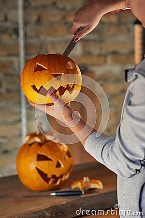 Woman carving Halloween pumpikn; Halloween pumpkin with a carved face Stock Photo