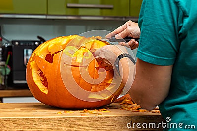 Woman carving a minion into a halloween pumpkin in the kitchen Stock Photo