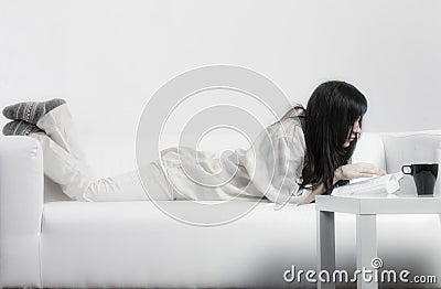 Woman in casual reading on couch Stock Photo