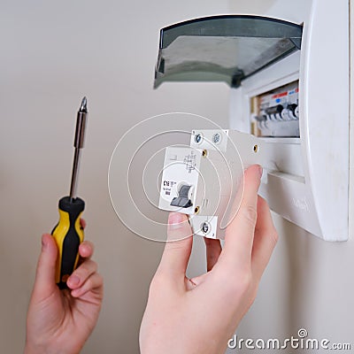 A woman changes an automatic fuse in a home electrical panel. Self repair and replacement of electricity equipment in the Stock Photo