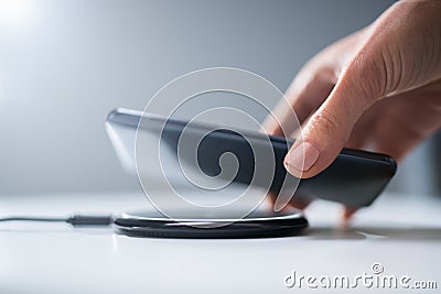 Woman Charging Smartphone Using Wireless Charging Pad Stock Photo