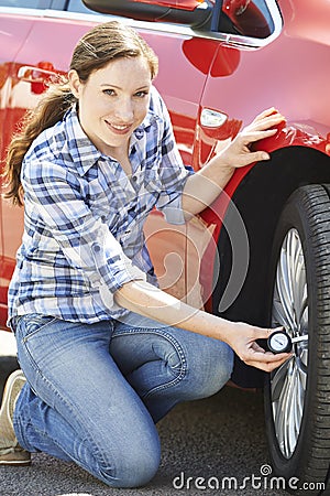 Portrait Of Woman Checking Car Tyre Pressure Using Gauge Stock Photo