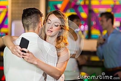 Woman checking her mobile phone while embracing a man Stock Photo