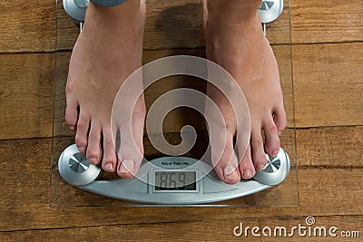 Woman checking her weight on a weighing machine Stock Photo