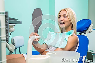 Woman checking teeth in mirror. Female at the dentist office. Stock Photo