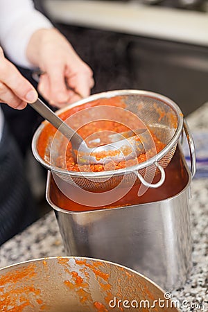 Woman chef whisking boiled tomato sauce Stock Photo