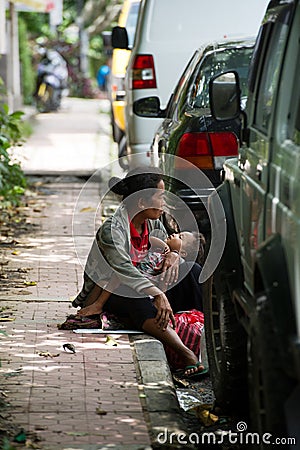 Woman with a child on a curb in Bali, Indonesia. Editorial Stock Photo