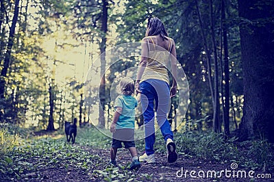 Woman and child walking a dog in the forest Stock Photo