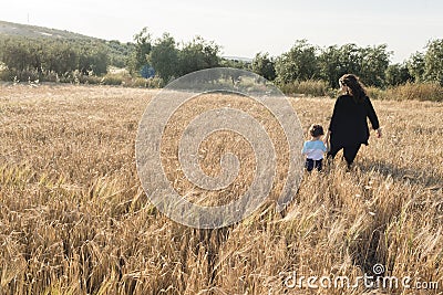 A woman and a child walking through a wheal field Stock Photo