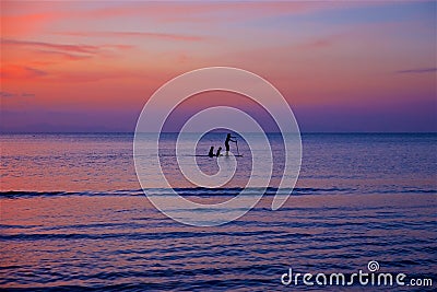 a woman and children swim on the sea on a board with a paddle Stock Photo