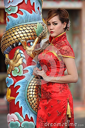 Woman in Chinese dress stand beside a pole Stock Photo