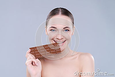 Woman, chocolate and bite in studio portrait with smile, eating and skin glow for beauty by Stock Photo