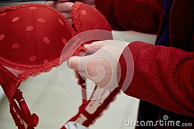 Woman chooses a big red bra in a clothing store. Hands close up shot Stock Photo