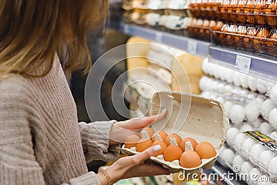 Woman chooses chicken eggs in a farm food store. Food consumption, Easter Stock Photo