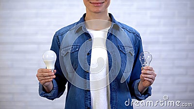 Woman choosing between energy saving led bulb and incandescent lamp, efficiency Stock Photo