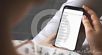 Woman choosing the language on her new mobile phone, language settings on smartphones Stock Photo